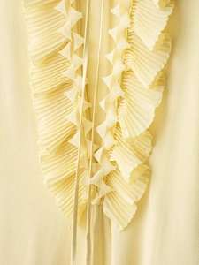 Detailed view of light yellow chiffon blouse featuring tiered ruffles and soft pleats
