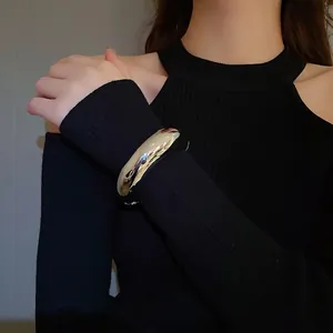 Polished silver adjustable chunky bangle bracelet worn over a black sweater sleeve