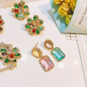 Vue détaillée de boucles d'oreilles baroques avec pierres colorées et montures dorées