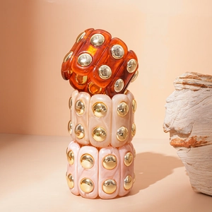 Detail of three acrylic resin stretch bracelets with marble textures and gold metal studs