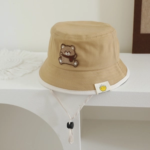 Detail of baby khaki sun hat featuring cute bear patch and adjustable chin strap