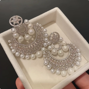 Detailed view of luxury silver flower pearl earrings with crystals on black background
