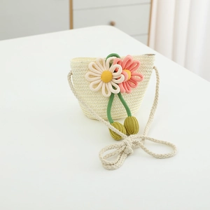 Detailed view of kids' straw crossbody bag with handmade floral accents and woven strap