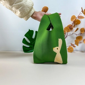 Detail of green knitted tote bag with white rabbit pattern and thick stitch texture