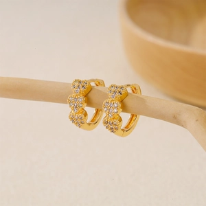 Macro detail of triple heart gold earrings with pavé white cubic zirconia inlay