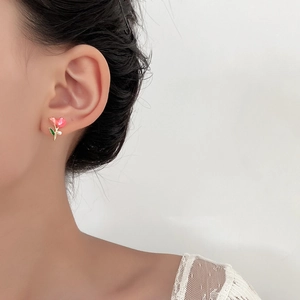 Nahaufnahme der rosa Blumen-Ohrstecker mit weißer Perle am Ohr des Models