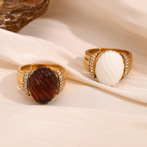 Detail of vintage 18K gold plated oval resin rings with side diamonds on beige silk