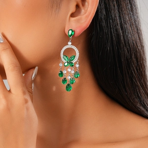 Close-up of elegant green teardrop tassel earrings with butterfly cubic zirconia accents
