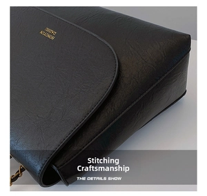Close-up of black leather bag showing precise stitching and golden logo detail