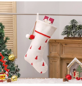 Close-up of a white plush Christmas stocking with red tree embroidery and festive gift box