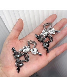 Macro view of 4-piece heart crystal bow hair clips in silver and gun-black finishes