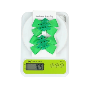 Weight display of two green Christmas tree bow hair clips on a scale showing 10.9g