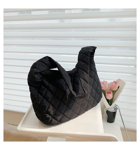 Detail of black quilted cloud bag with knot handle and elegant ruched texture