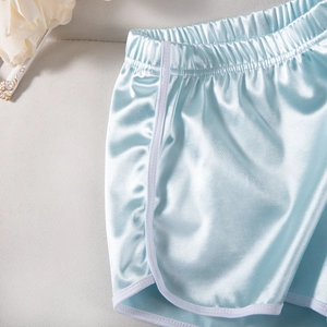Detail of light blue satin sports shorts with elastic waistband and white piping