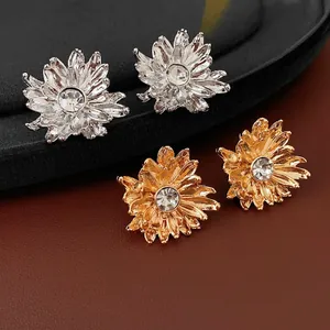 Elegant gold and silver floral stud earrings with rhinestones on a luxury display stand