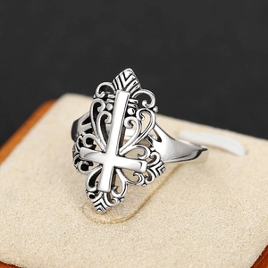 Macro detail of gothic silver ring featuring hollow wave patterns and a reverse cross