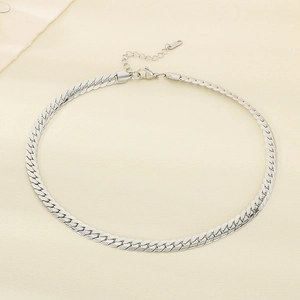 Close-up of flat silver Cuban link chain necklace with lobster clasp on beige fabric