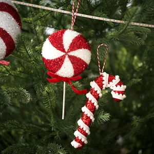 Red and white candy cane Christmas tree ornaments with glitter on green branches