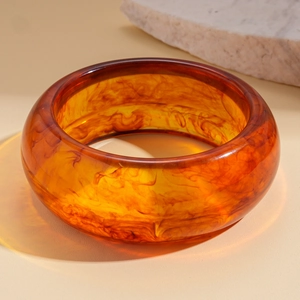 Macro shot of amber resin geometric bangle with tortoise shell texture on beige background