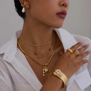 Gros plan sur un ensemble de bijoux dorés avec perles, collier, boucles et bague