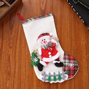 Close-up of linen Christmas stocking with Santa doll and sequin tree on wood floor