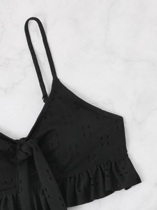 Detail of black eyelet embroidery on bikini top with bow tie and ruffle hem