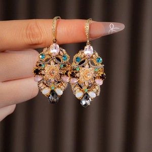 Detailed close-up of vintage gold earrings with multi-colored crystals and floral patterns