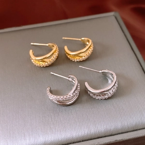 Detail view of gold and silver double-layered C-shaped earrings with sparkling cubic zirconia