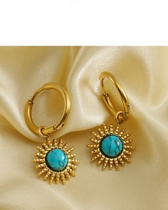 Detail of 18K gold plated sunflower earrings with turquoise stone on silk fabric