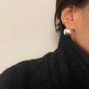 Macro shot of large polished silver sphere earrings on model with black turtleneck