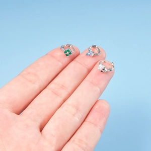 Detailed set of butterfly, clover and skull stud earrings held between fingers