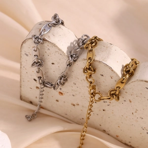 Detail of gold and silver thick link bracelets displayed on a stone arch prop