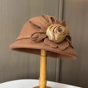 Detail eines karamellfarbenen Wollhutes mit Satinblume und dezentem Netzschleier