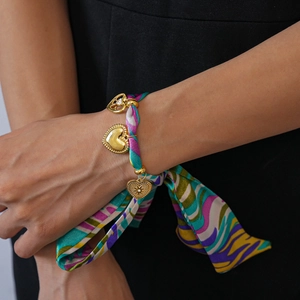 Detail of silk scarf bracelet with golden heart pendants and colorful fabric patterns