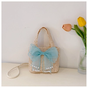 Detail of beige straw kids bag featuring a large blue mesh bow with white pearls