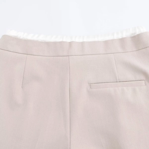 Close-up of the beige wide-leg trousers showing the waistband and back welt pocket detail