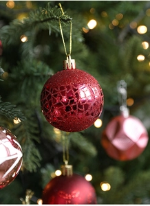 Macro detail of red Christmas ball with geometric patterns hanging on a pine tree branch