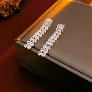 Detailed macro view of silver tassel earrings with rows of clear cubic zirconia on a box