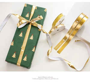 Detail of gold and white Merry Christmas ribbons used on a dark green gift box