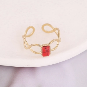 Detailed macro view of an adjustable gold ring featuring a red stone with woven band