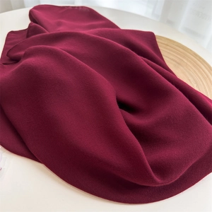 Detailed close-up of dark red cotton linen scarf texture on a wooden tray