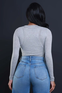 Detail of grey slim knit top with curved back stitching and high waist jeans on a model