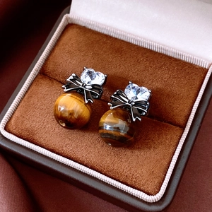 Macro shot of tiger eye stone earrings with black bow and heart zircon in a velvet box