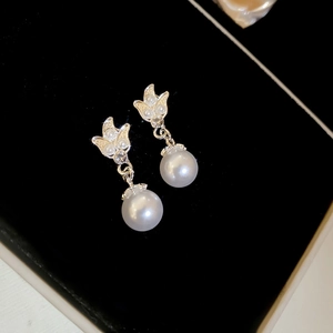 Detail of bow-knot pearl earrings with zircon inlay presented in a premium black jewelry box