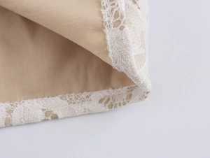 Close-up of beige woven cotton fabric featuring delicate white lace trim details