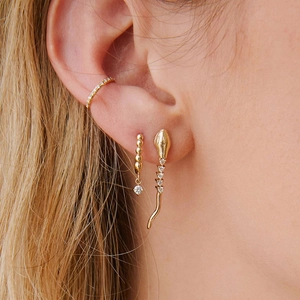 Detail of 18k gold cobra snake earrings set with zircon studs and tassel design