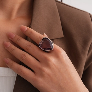 Détail d'une grande bague cœur en zircon violet portée par un mannequin en veste marron