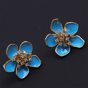 Detailed close-up of blue flower earrings with gold edges and sparkling zircon centers