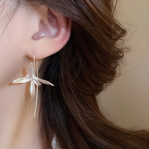 Close-up of elegant silver iris flower drop earrings worn by a model in soft lighting