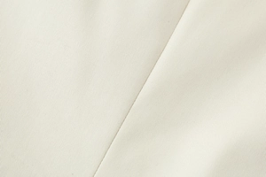 Close-up of beige fabric showing fine twill texture and diagonal stitching details